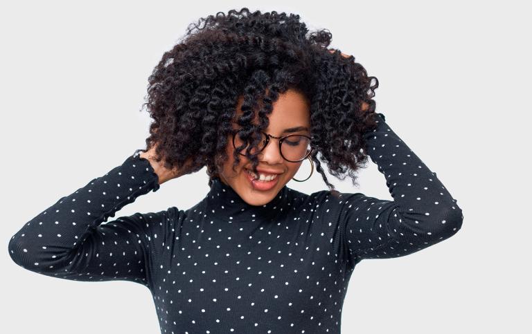 African American female smiling broadly with her hands in her beautiful, healthy hair.